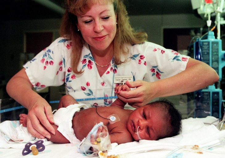 Mujer sosteniendo la mano de un bebé que rescató de ser enterrado vivo 