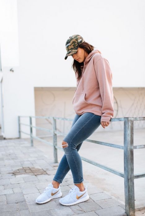 Chica usando jeans y sudadera de color rosa palo 